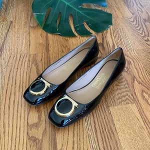 Salvatore Ferragamo black patent flats with gold logo piece.